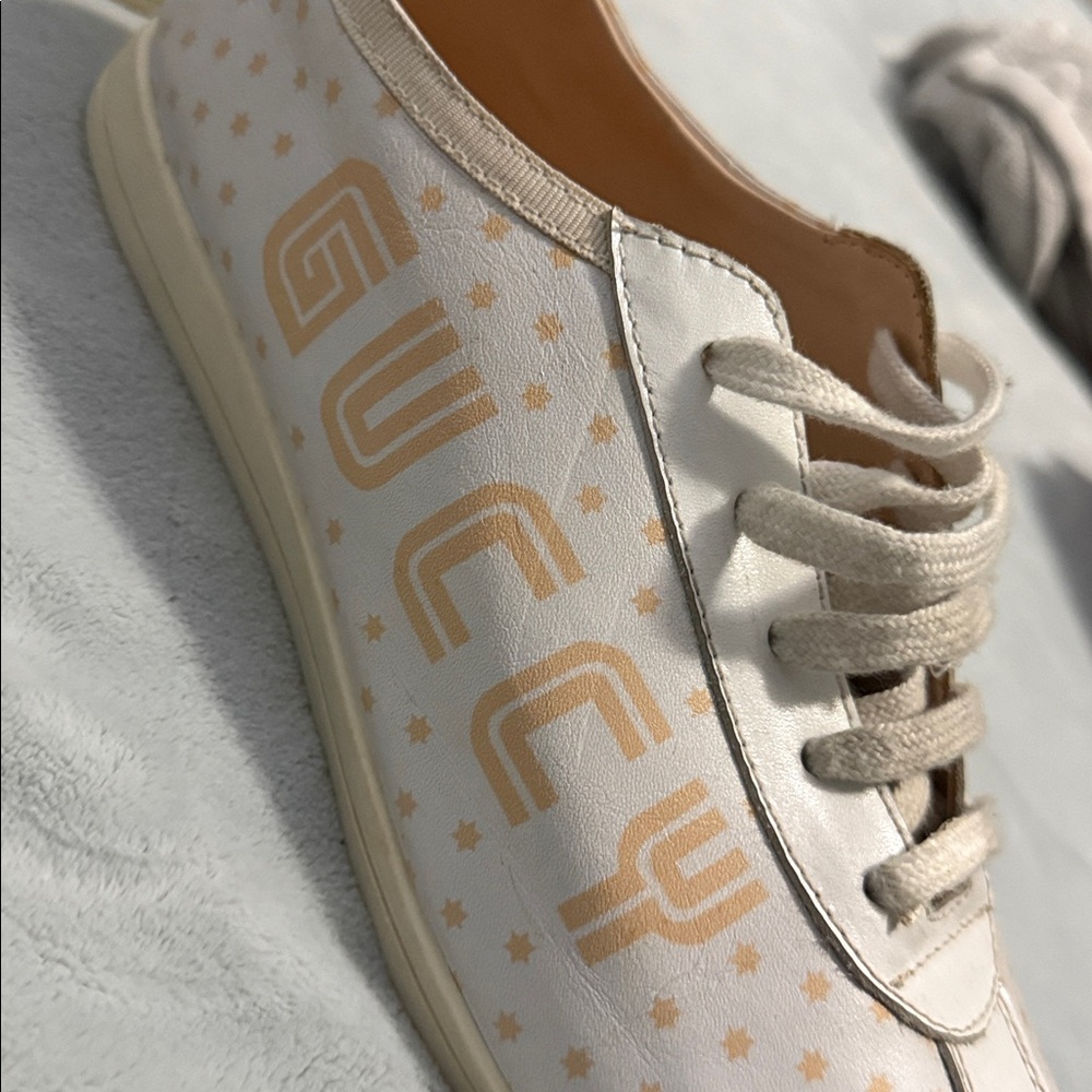 GUCCI Falacer low-top sneaker in white leatherprint in gold and star detailing.